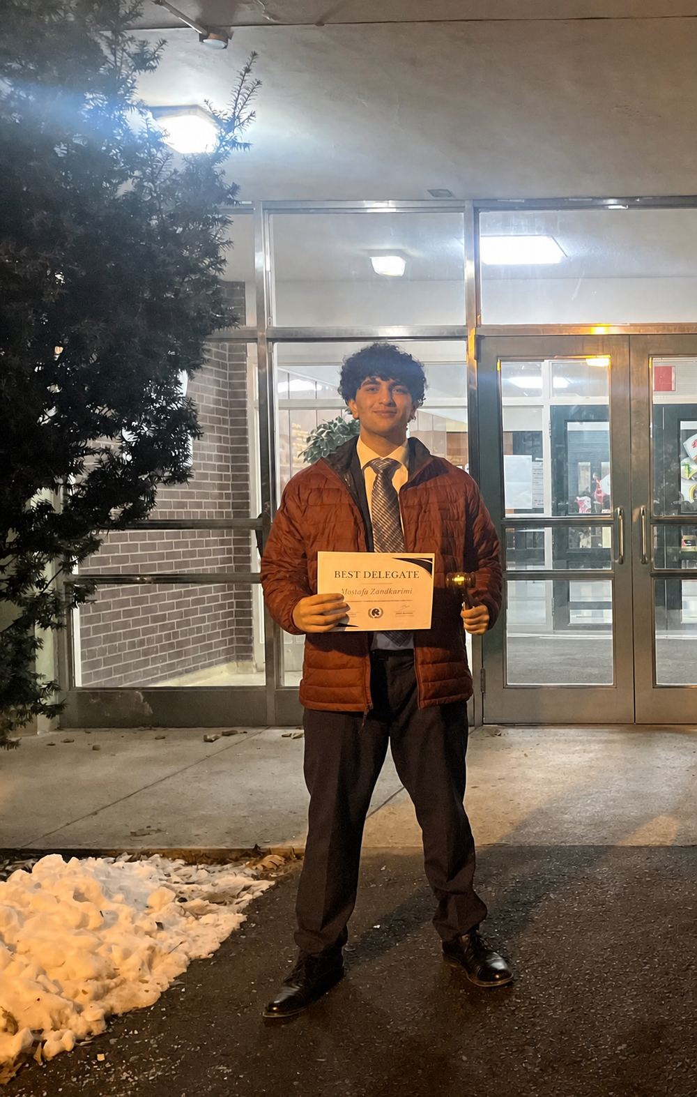 Mostafa Zandkarimi holding a Best Delegate certificate